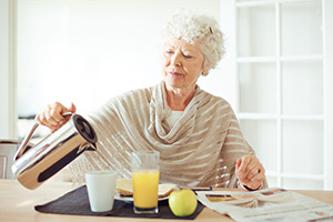 Elderly woman pouring juice for breakfast